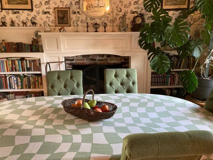 Basket with fruit on a checkered tablecloth in a cozy room with bookshelves and a fireplace