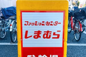 Sign in Japanese language on a stand; bicycles parked in the background