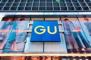 Sign of GU fashion store with ads featuring models in casual clothing on building façade