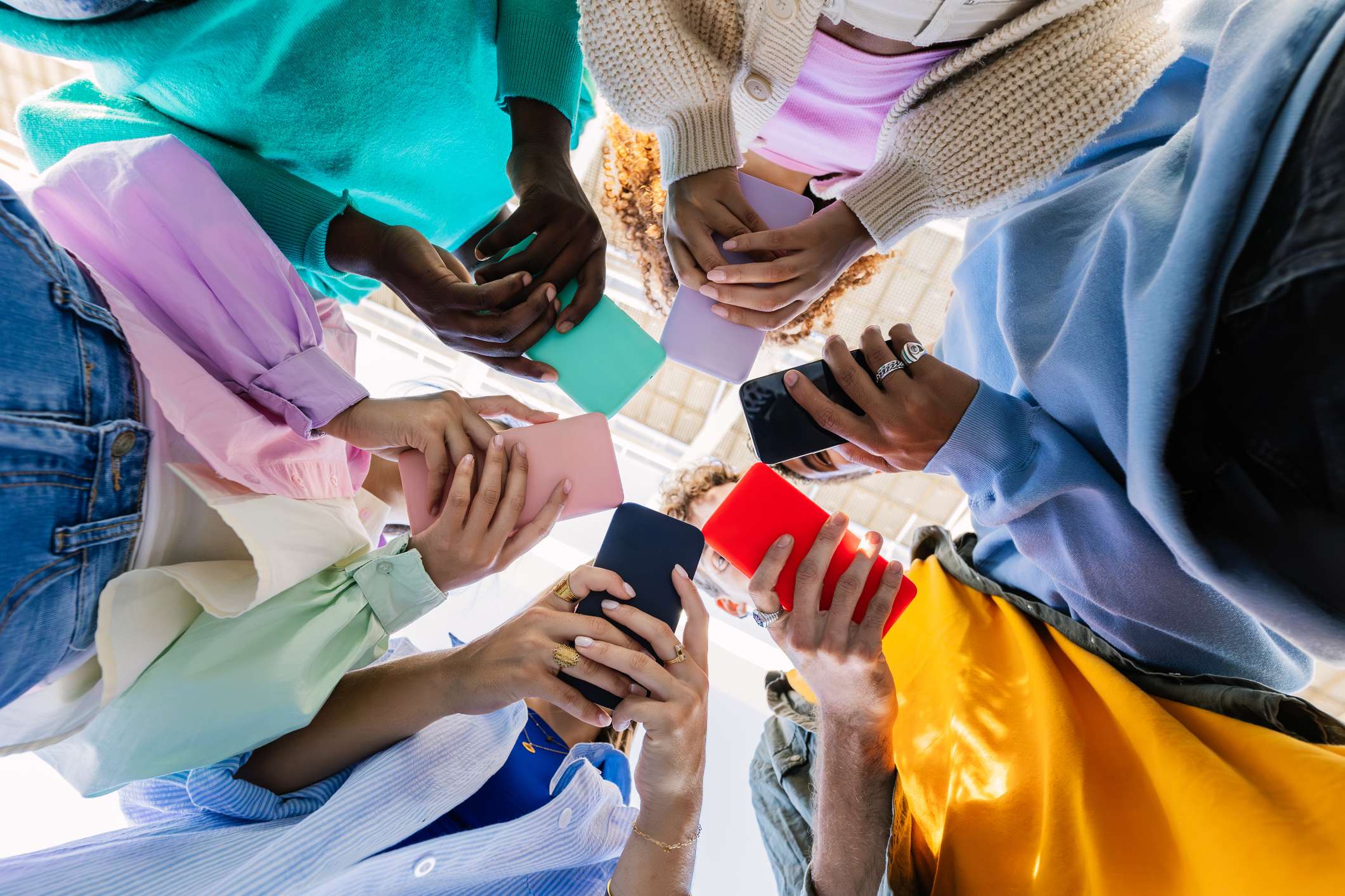 Group of people in casual wear standing in a circle, holding smartphones