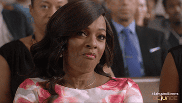 Woman in a floral dress giving a side-eye expression at an event