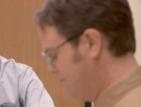 A man at a desk with a surprised expression, turning to look to his side