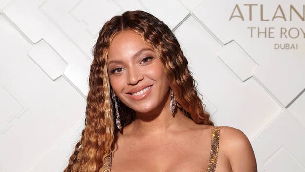 Beyoncé smiles at a music event, wearing a glittery strap dress