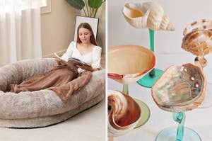 Woman lounging in a large, cozy cushioned pet bed while reading a book; artistic glass seashell sculptures on display