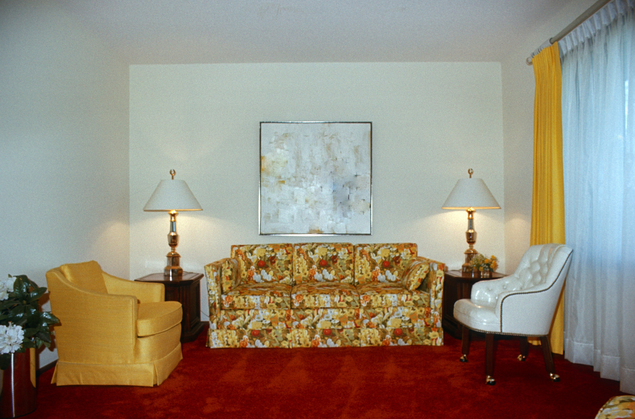 1970s living room with an abstract painting, floral couch, and a mix of armchairs
