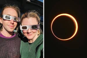 Two people wearing eclipse glasses smiling, with a solar eclipse visible on the right