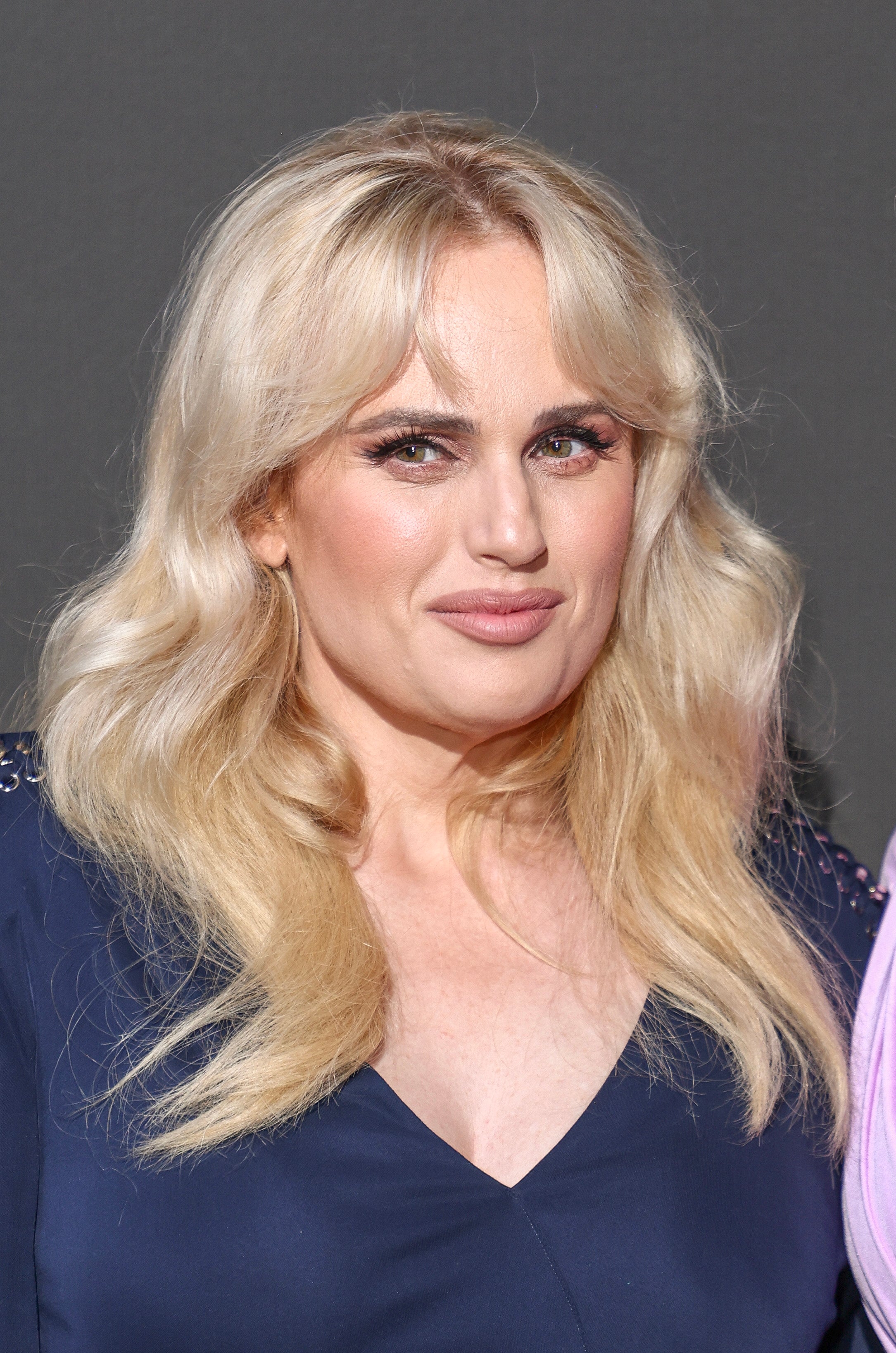 Rebel Wilson poses in a dress with wavy blonde hair