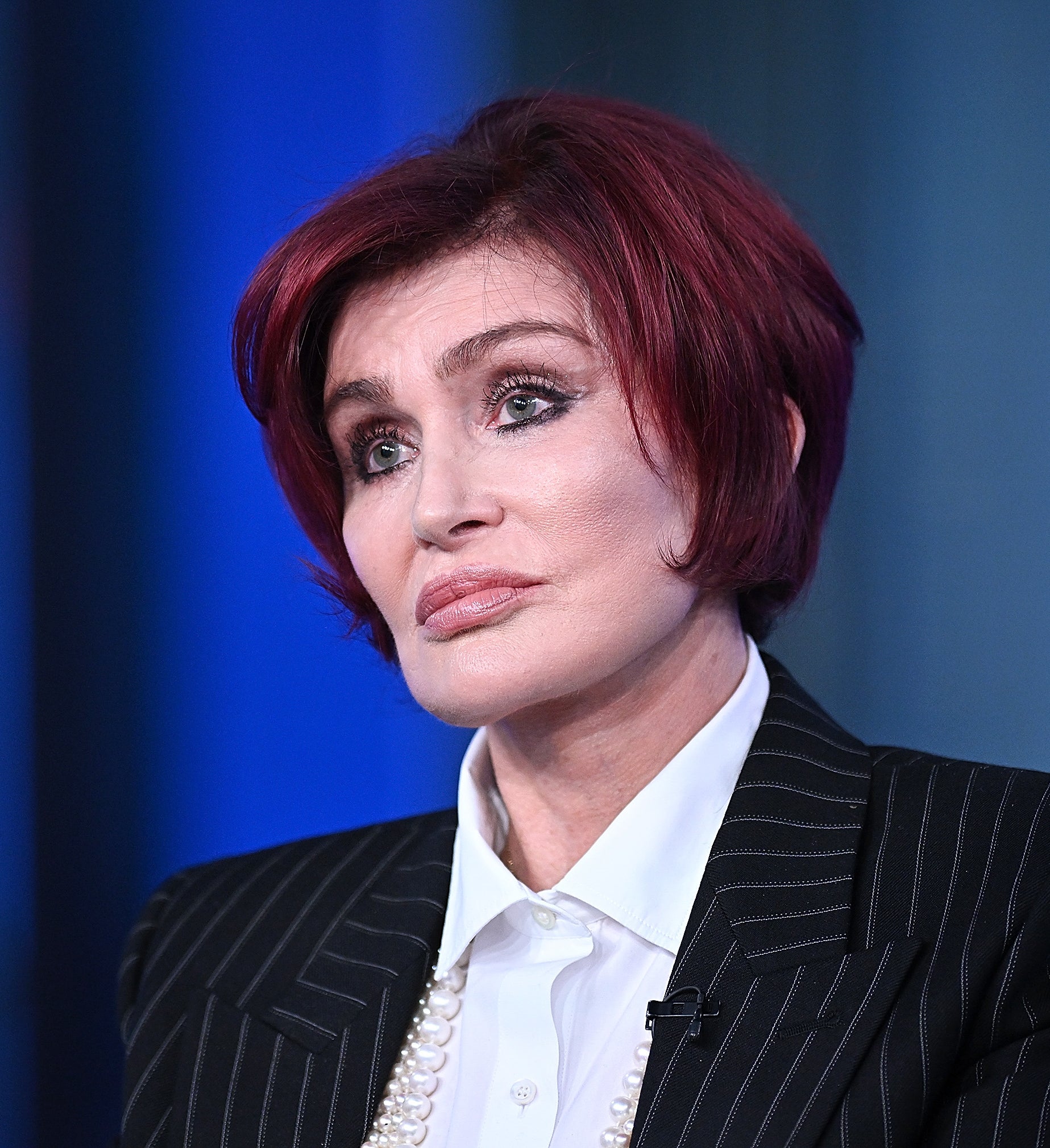 Sharon Osbourne in a pinstripe suit with layered pearls