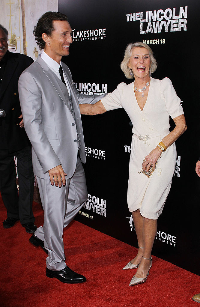 Matthew McConaughey in a suit smiling with his mom in a dress and pearl necklace at an event