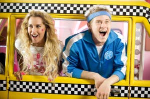 Sharpe and Ryan from High School Musical in a yellow bus with a checkered pink interior. They are smiling and posing playfully