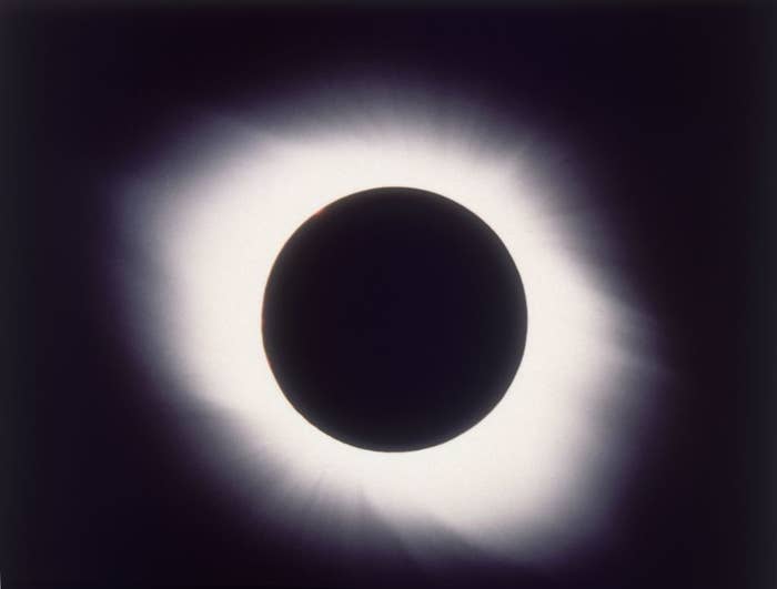 A solar eclipse with a prominent corona visible around the obscured sun