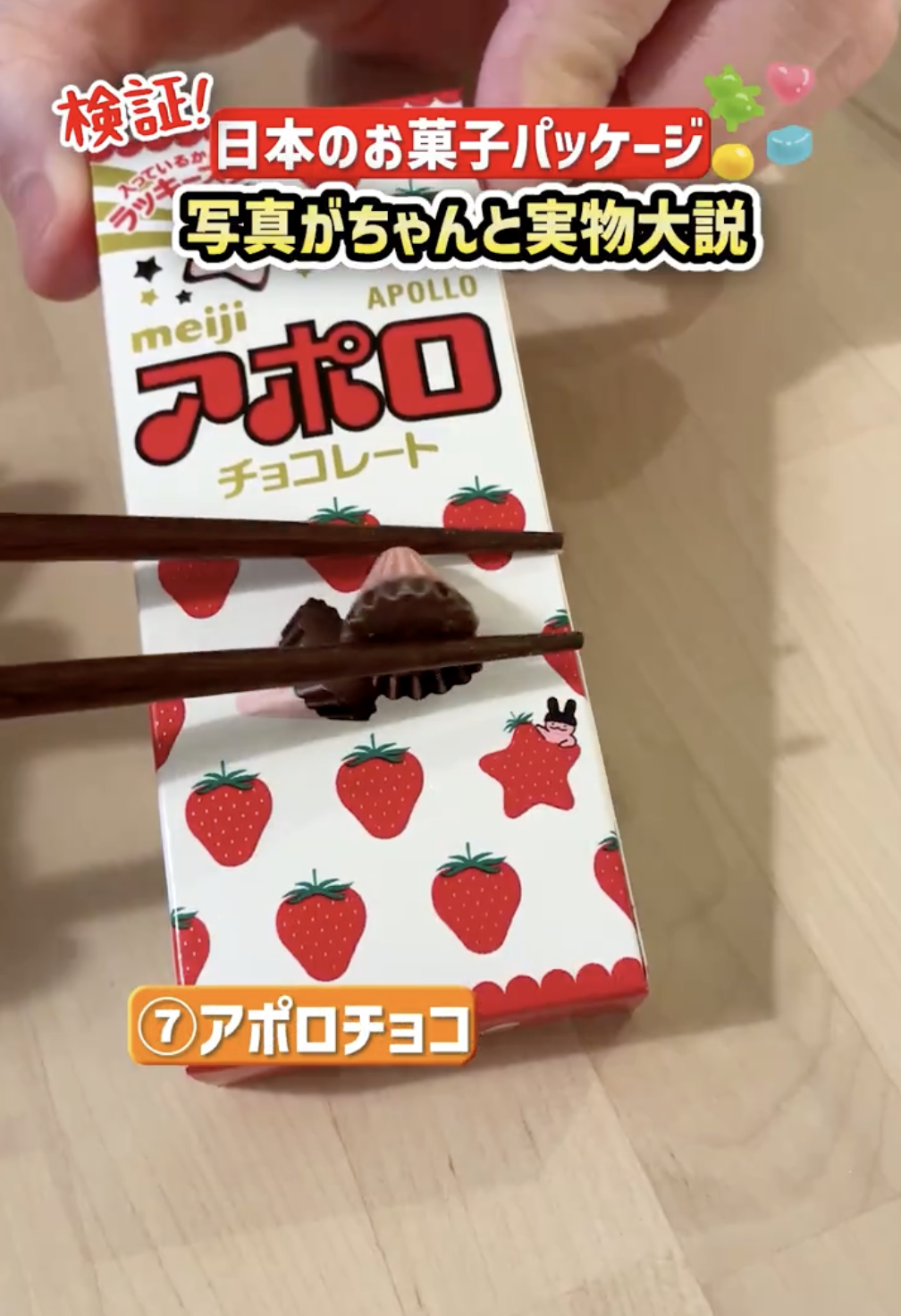 箸でつままれたチョコレートとそのパッケージ。Apolloブランドのイチゴ形チョコ。