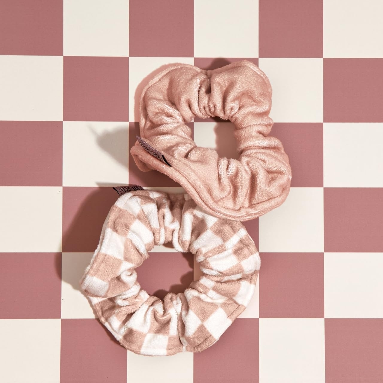 Two scrunchies with towel material on a checkered background