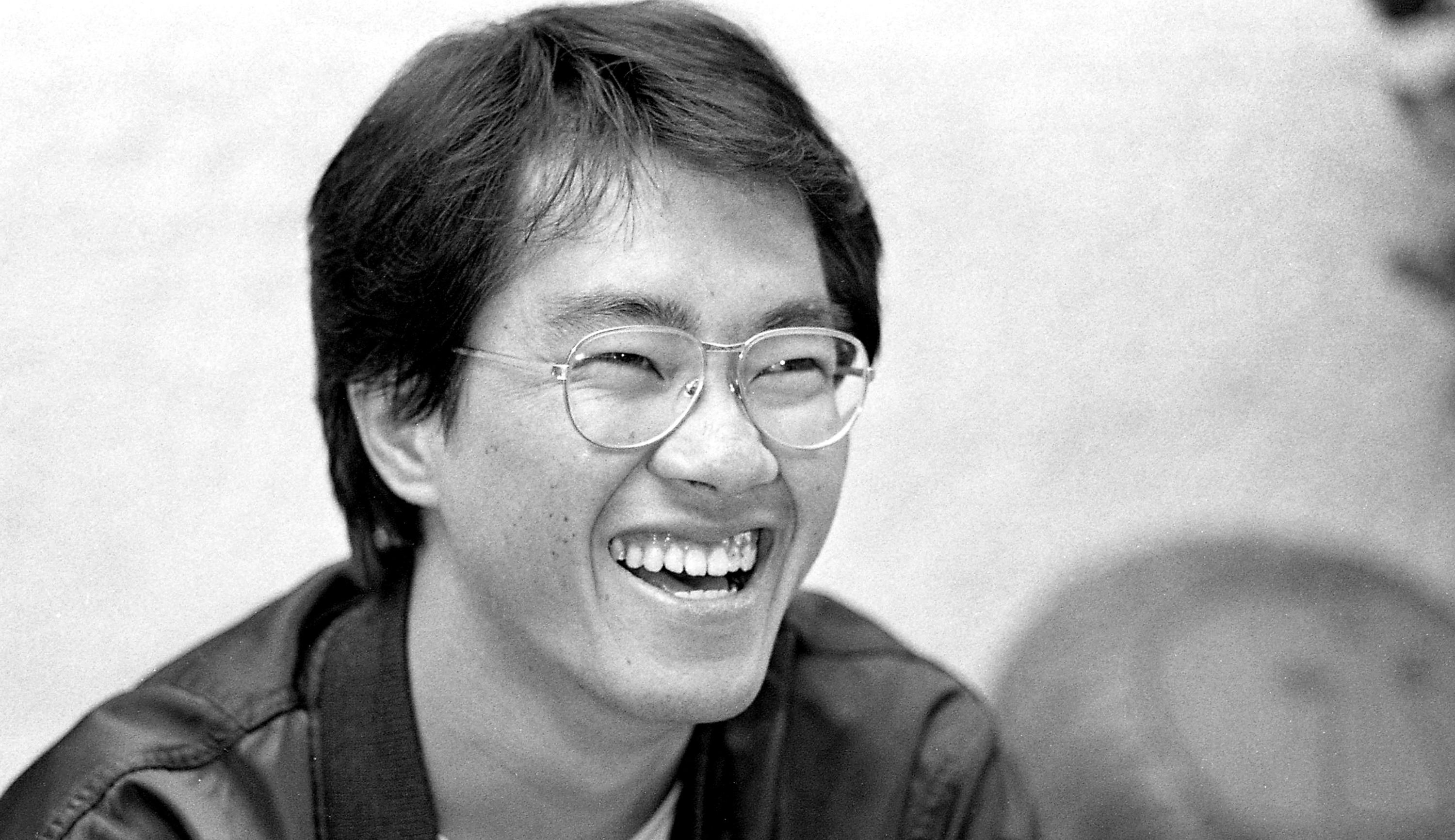 Man with glasses smiling, wearing a jacket, in a black and white photograph