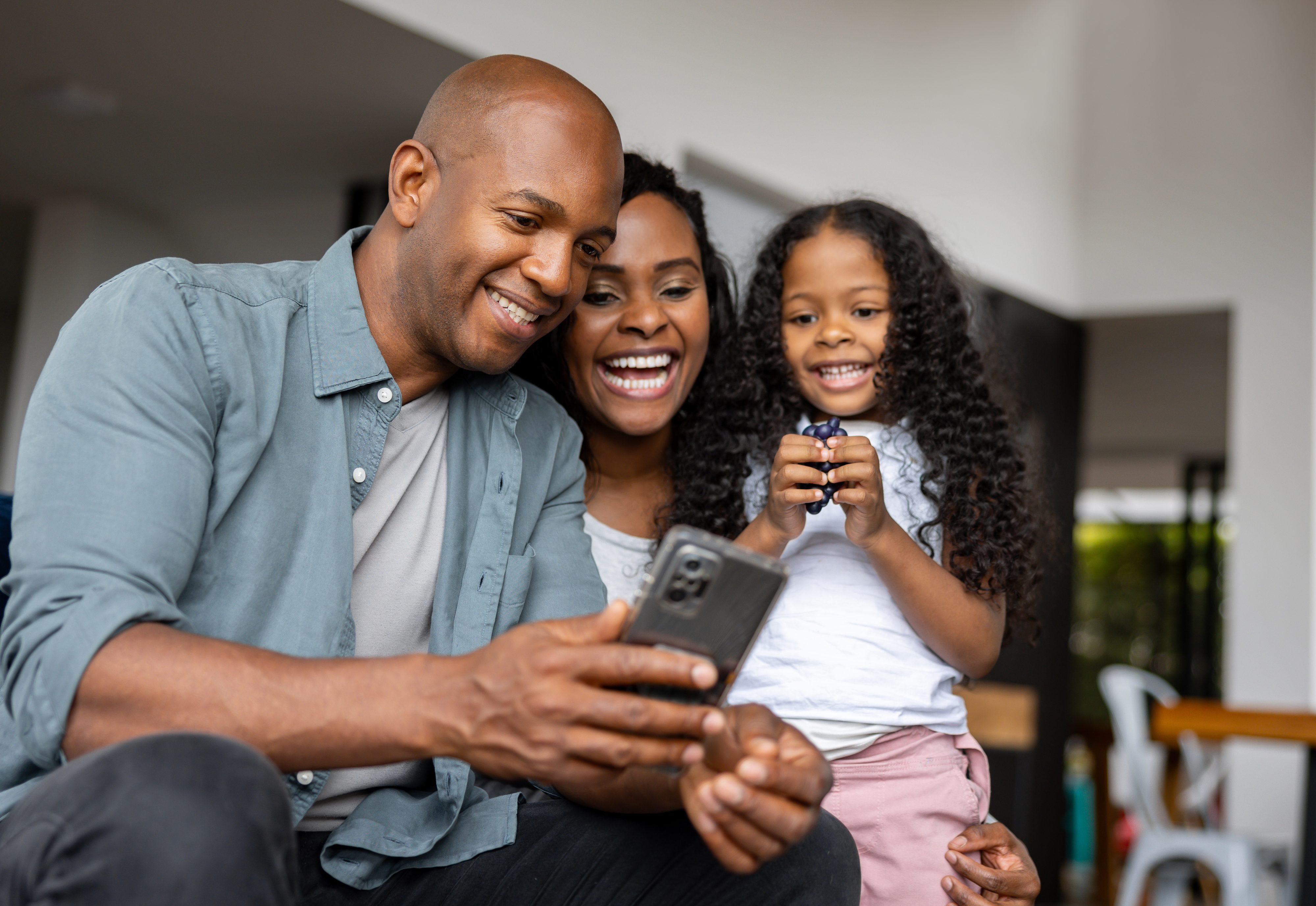 Family with child taking a selfie, showing joy and togetherness, in a home setting