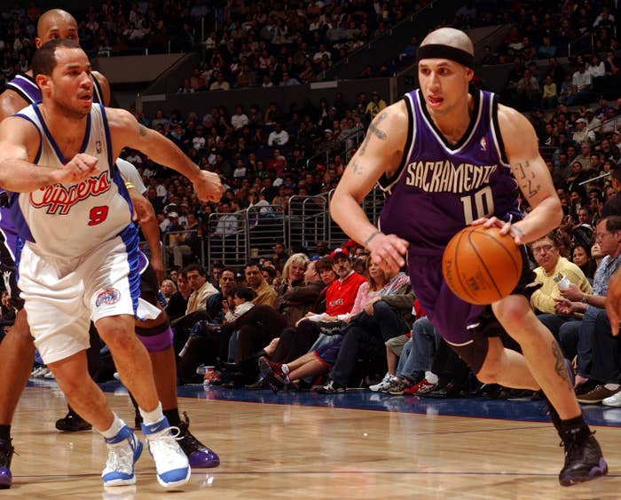 Two basketball players in action during a game, one defending as the other dribbles the ball