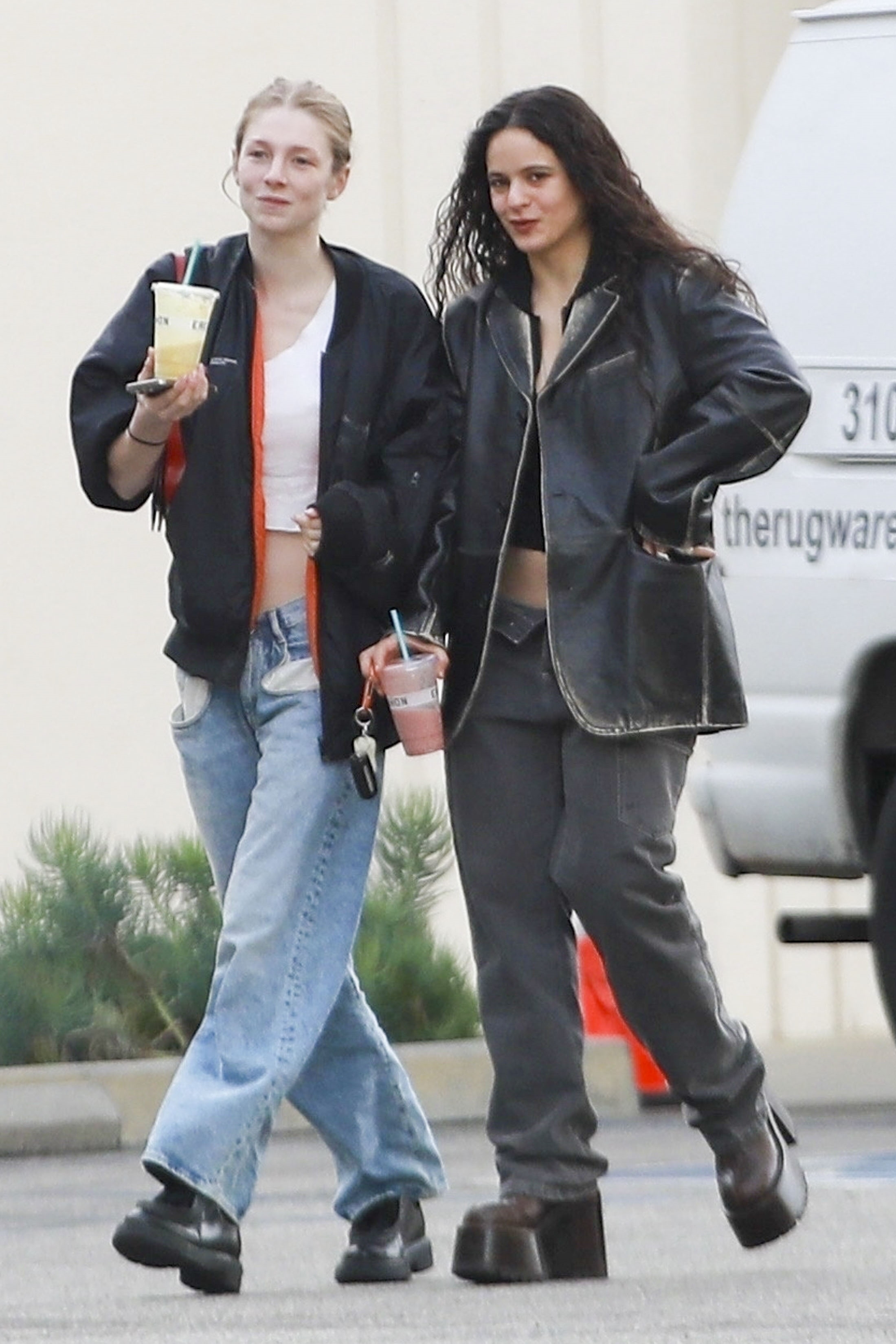 Hunter and Rosalía walking side by side outside as they sip on drinks