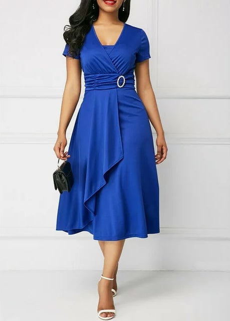 Model in a blue mid-length dress with a v-neck, short sleeves, and belt detail, holding a purse, suitable for shopping