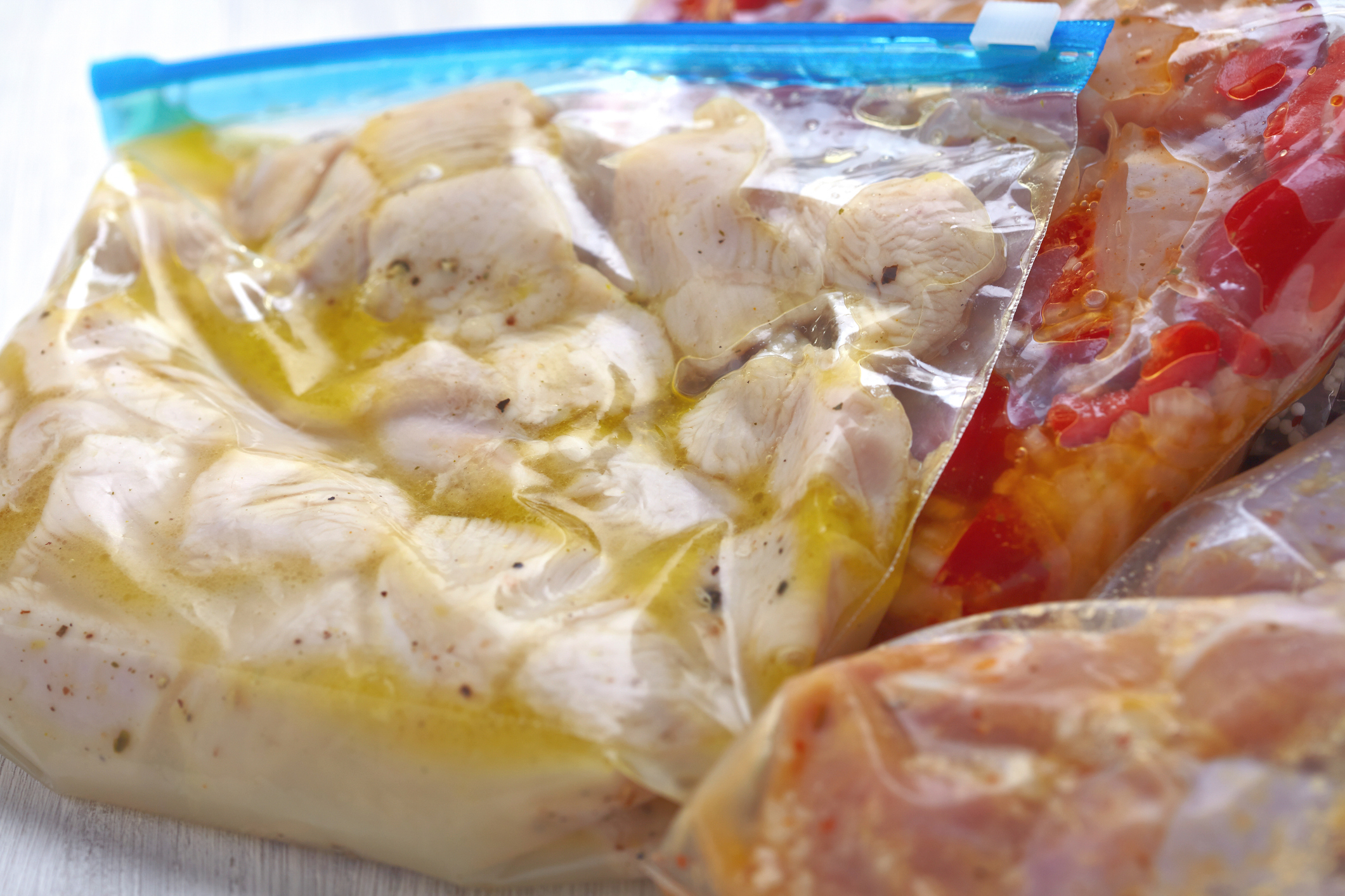 Chicken and vegetables marinated in separate sealed plastic bags, ready for cooking