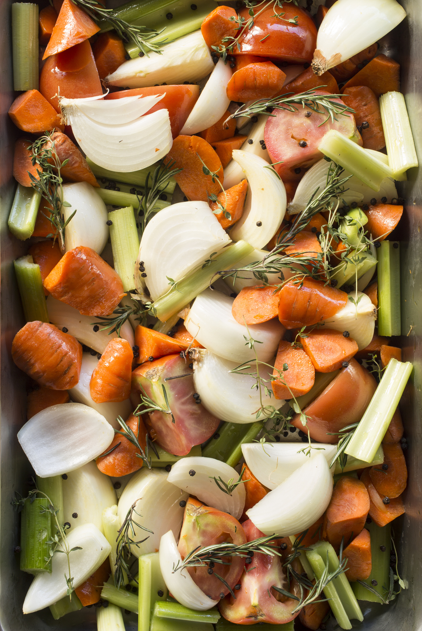 Assorted raw vegetables with herbs in a roasting pan, prepped for cooking
