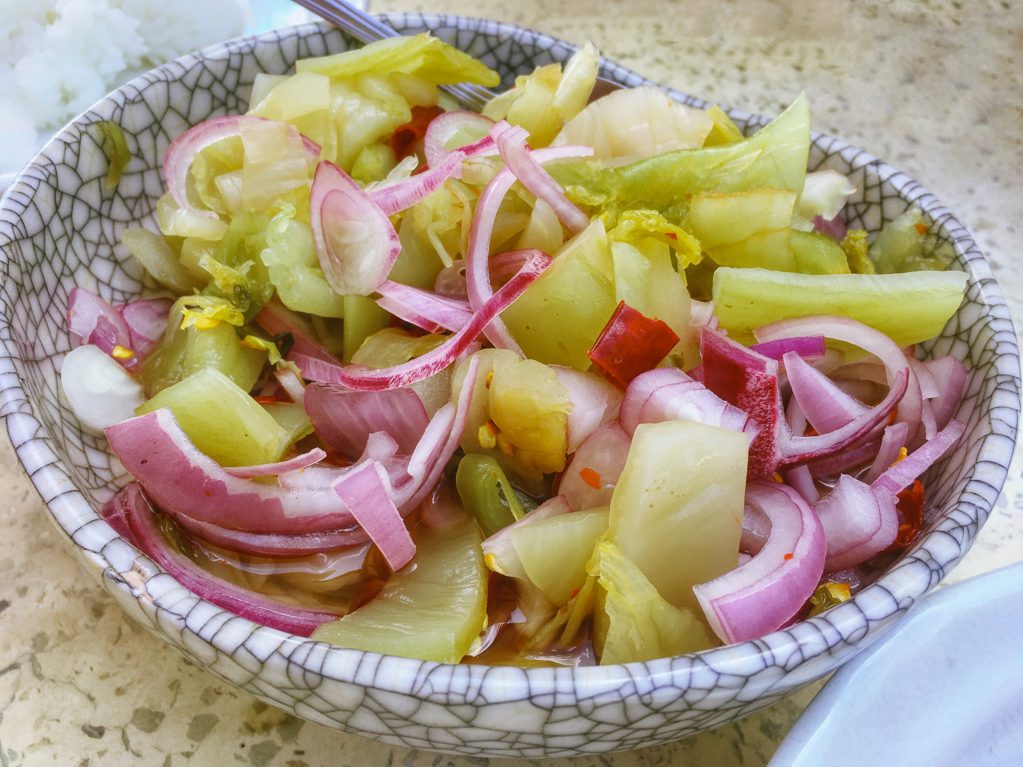 A bowl of mixed salad with sliced onions and lettuce