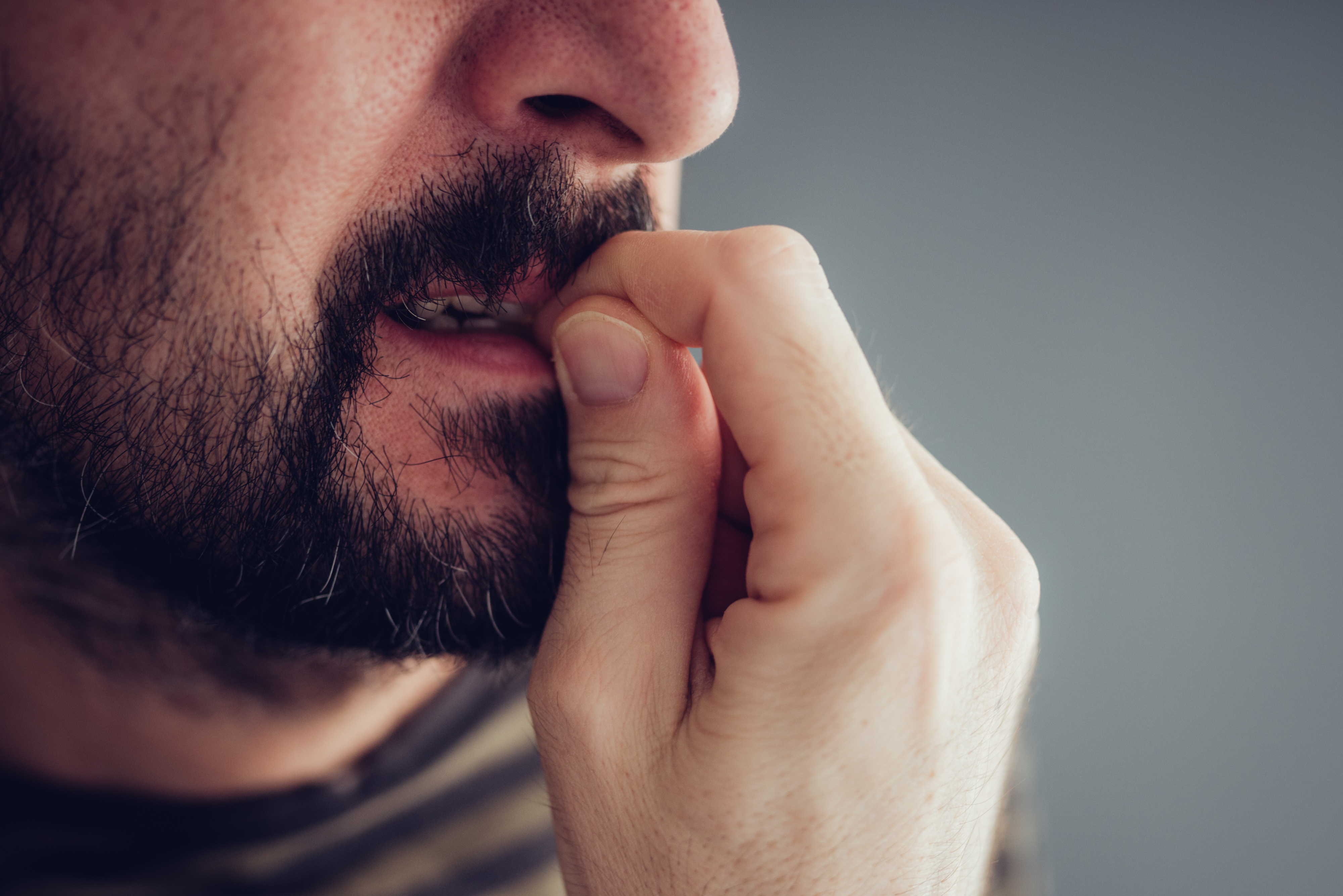 Person biting nails in a close-up, showing signs of anxiety or deep thought