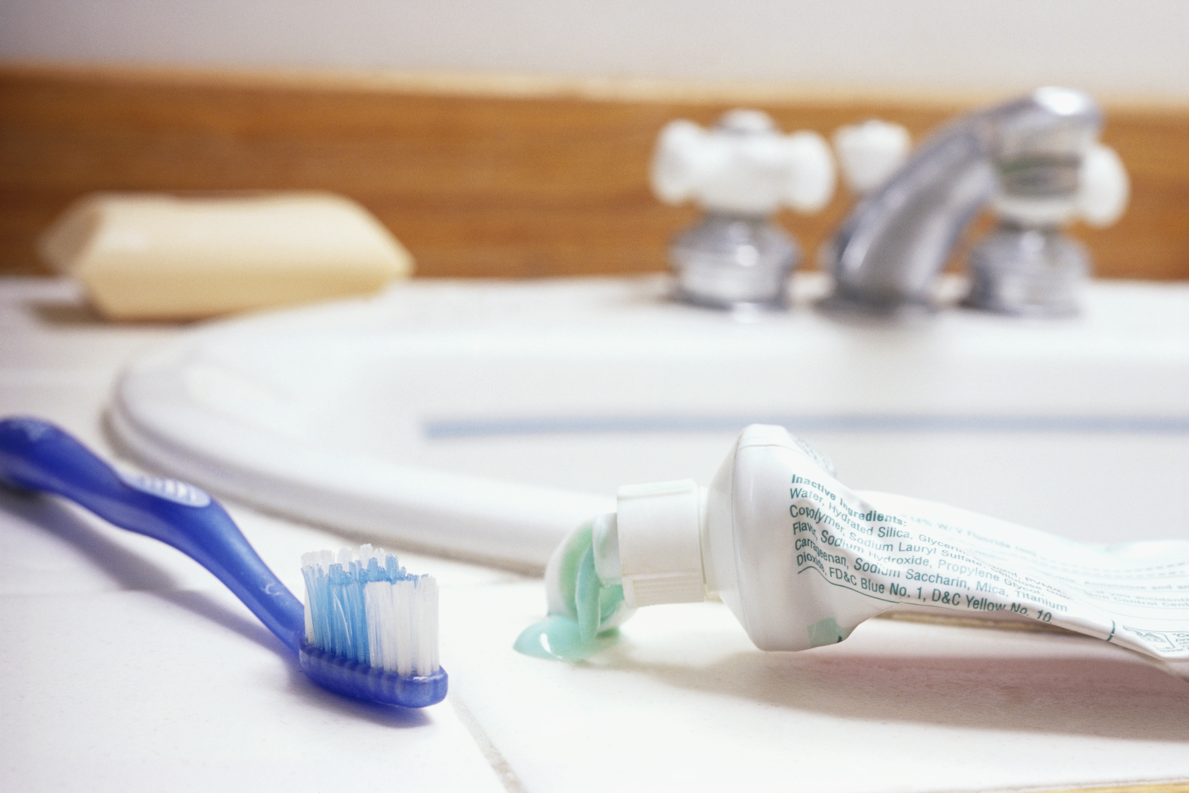 A toothbrush and toothpaste tube laying on a bathroom counter