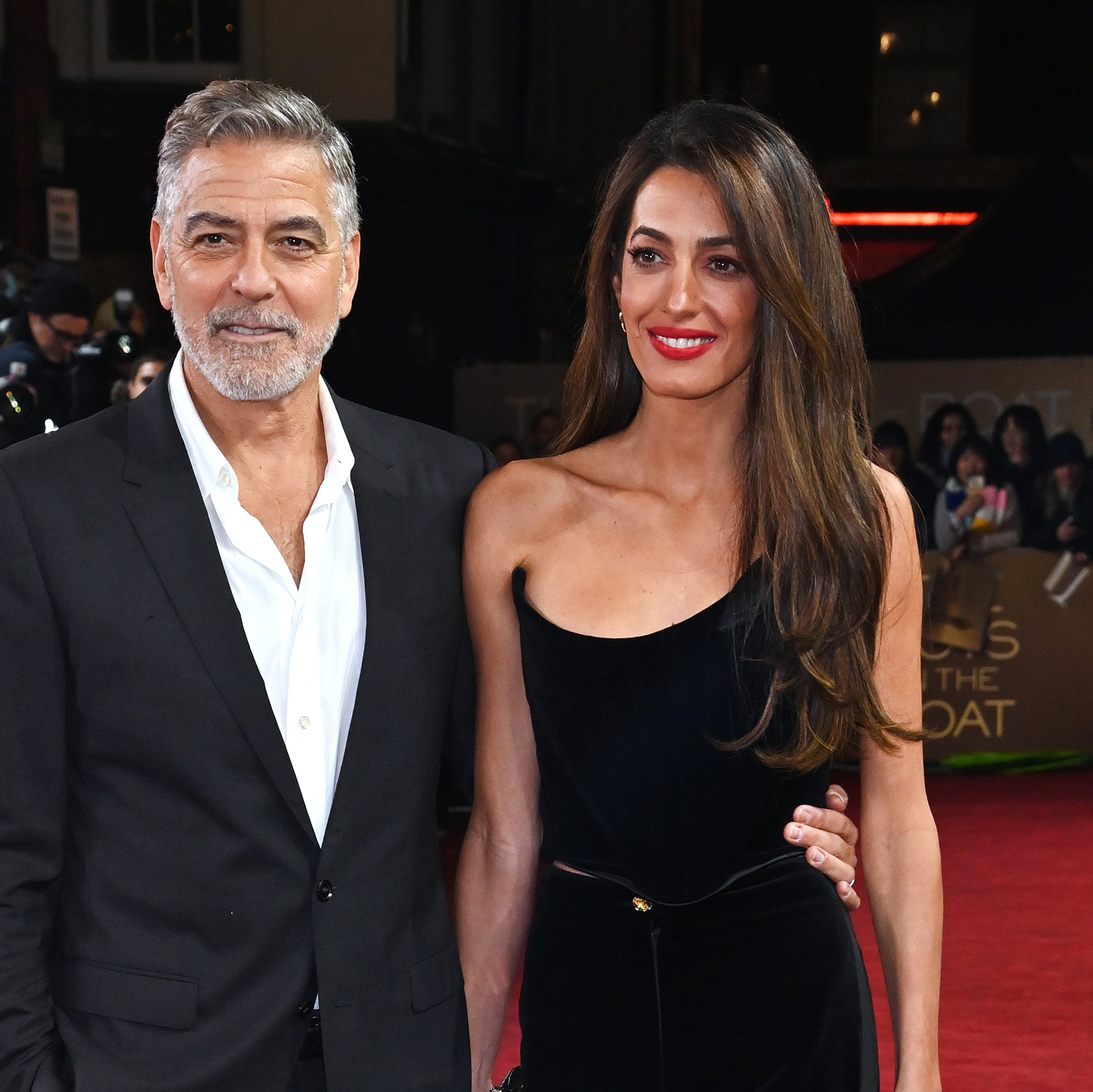 Two celebrities on the red carpet, with the male in a gray suit and the female in a sleek black dress