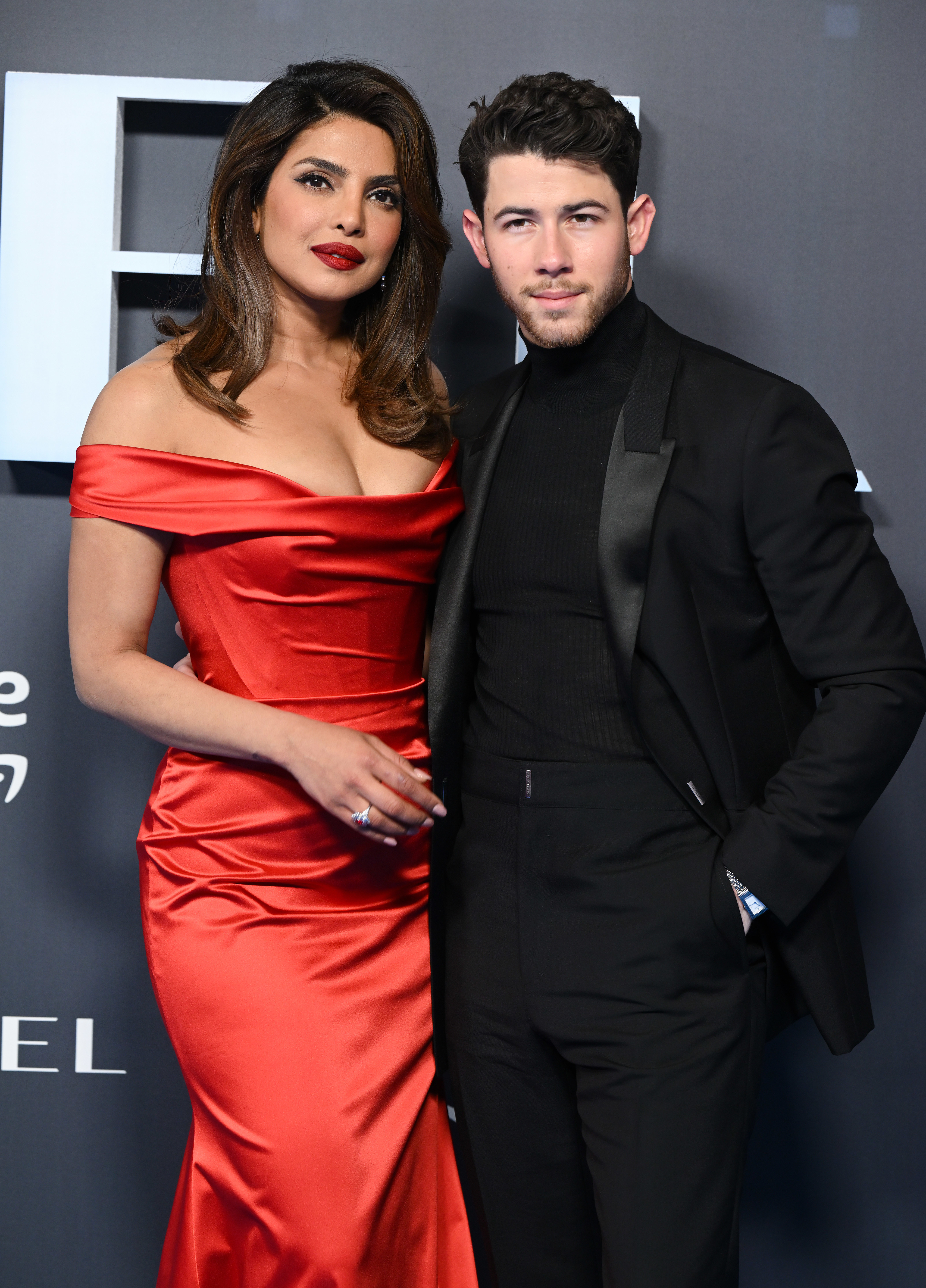 Priyanka Chopra in a satin off-shoulder gown and Nick Jonas in a sleek suit posing together