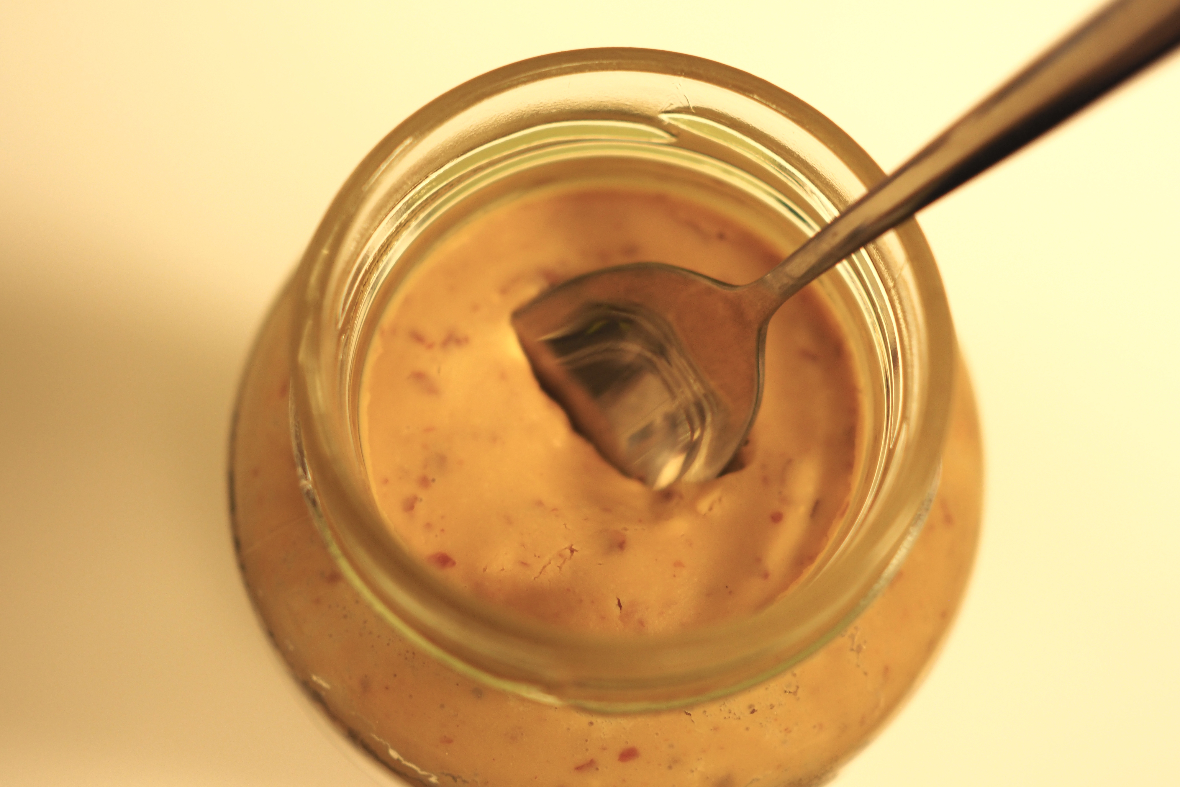 Top view of an open jar of peanut butter with a spoon inside