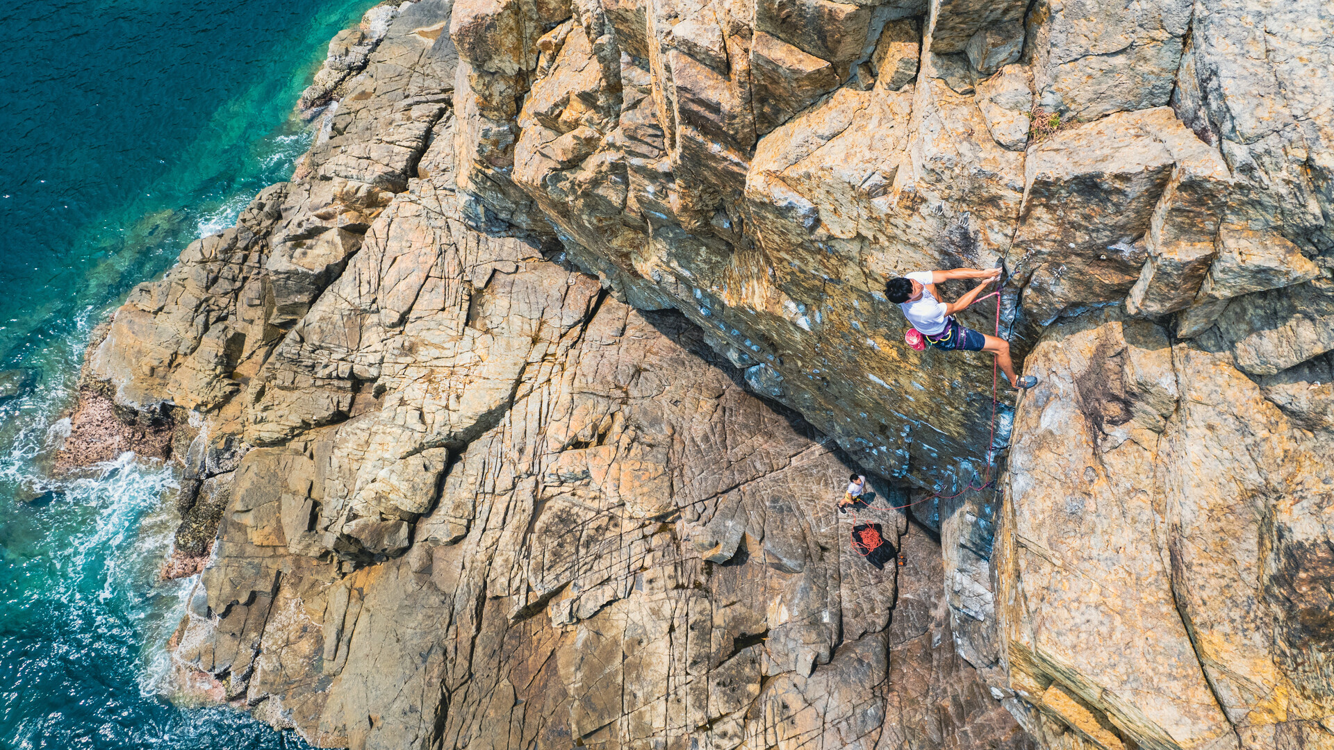 Person rock climbing a steep cliff above the sea
