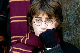 Daniel Radcliffe as Harry Potter in a scene, wearing glasses and a Gryffindor scarf