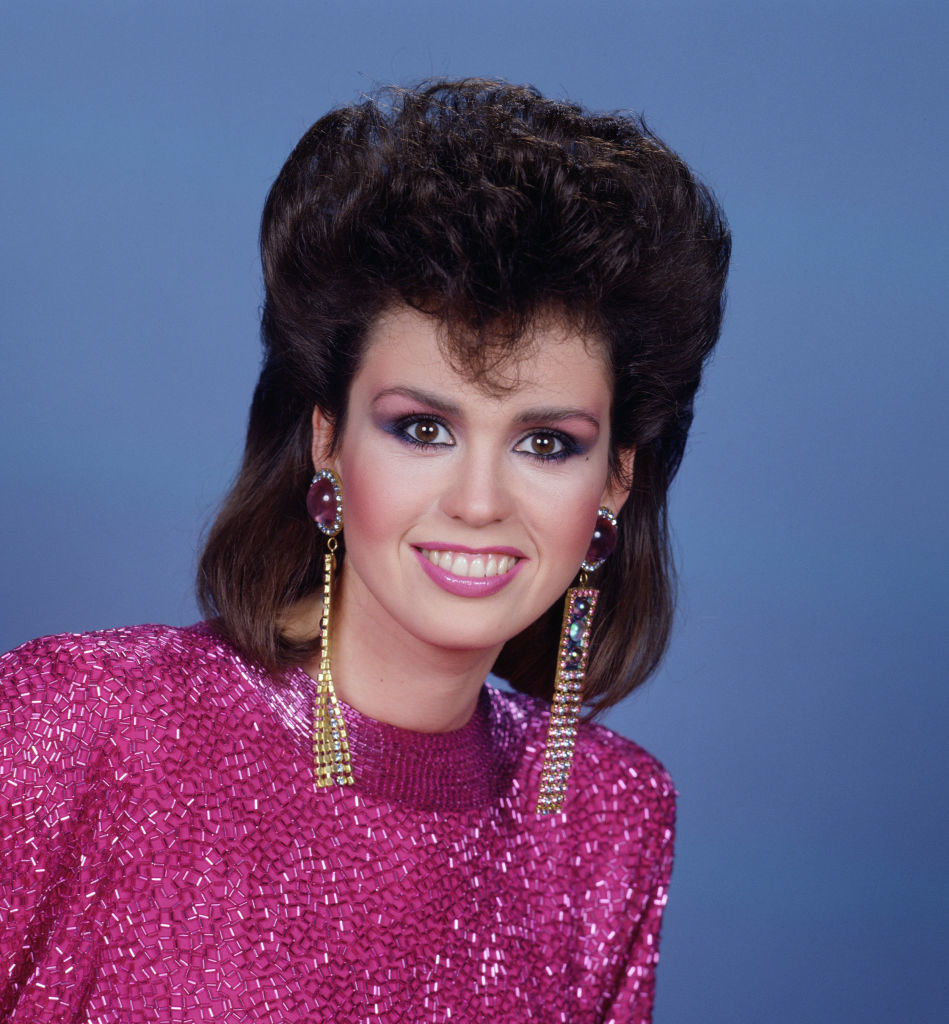 Woman in sparkly top with voluminous hair, embodying a retro '80s style