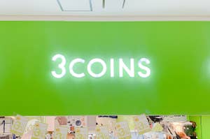 店舗の緑色の壁に「3COINS」と白い文字で表示されている看板です。