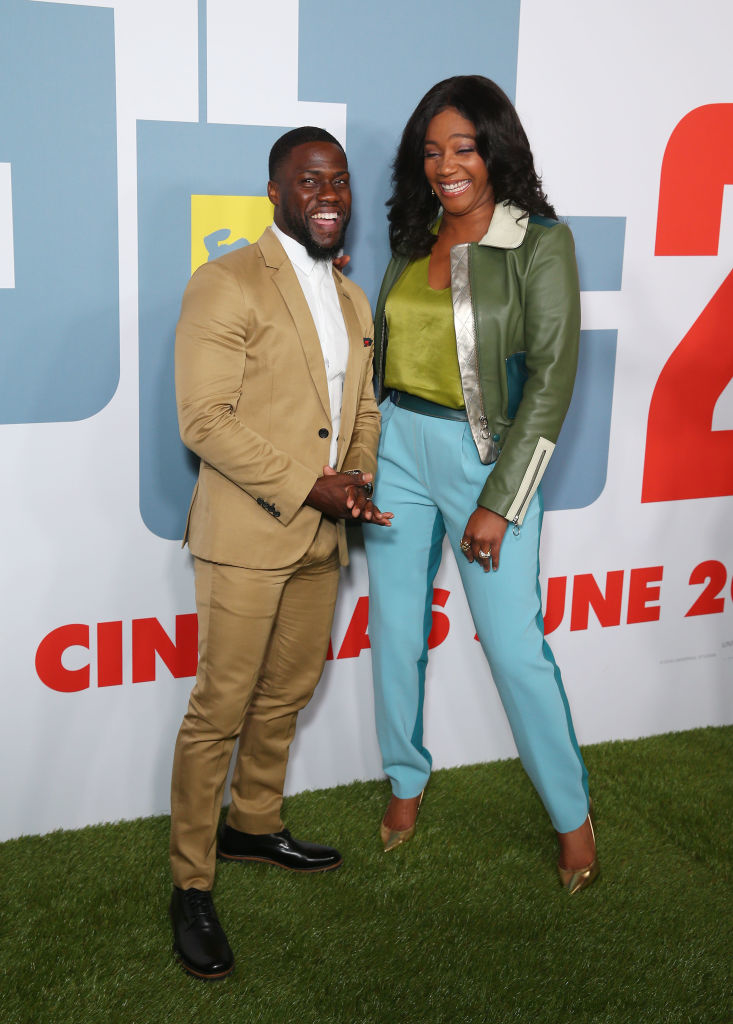Kevin Hart and Tiffany Haddish posing together; Kevin in a suit, Tiffany in a blouse and trousers