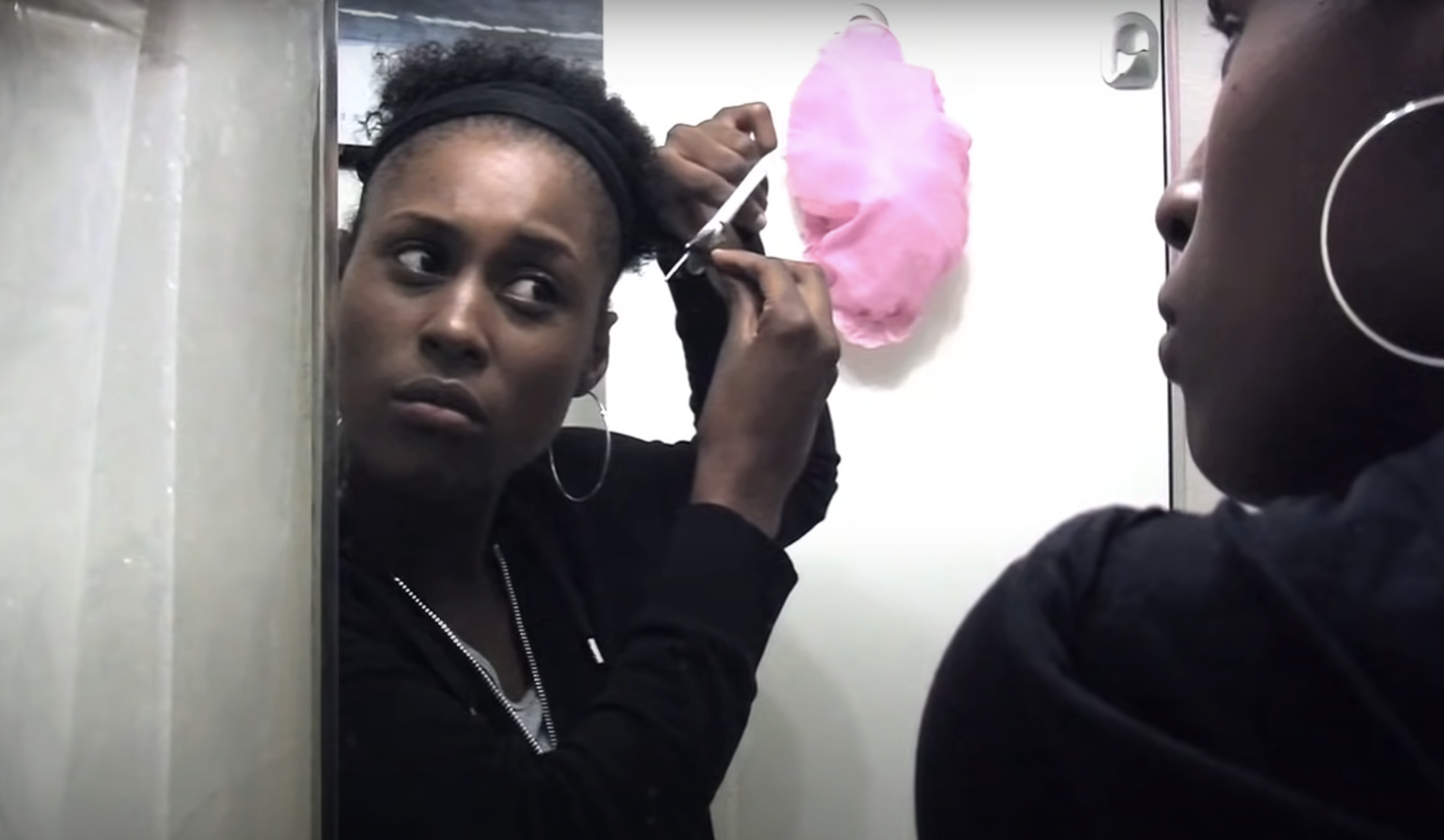 Issa Rae in a scene trimming her hair in the mirror