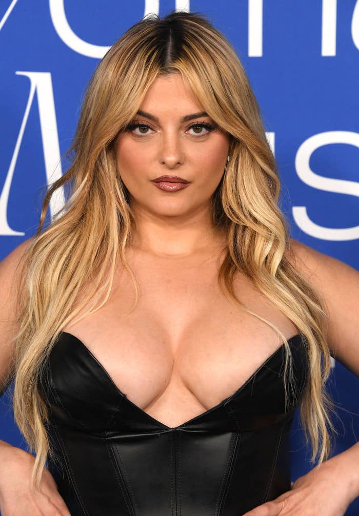 Addison Rae in a black leather dress on a photo wall