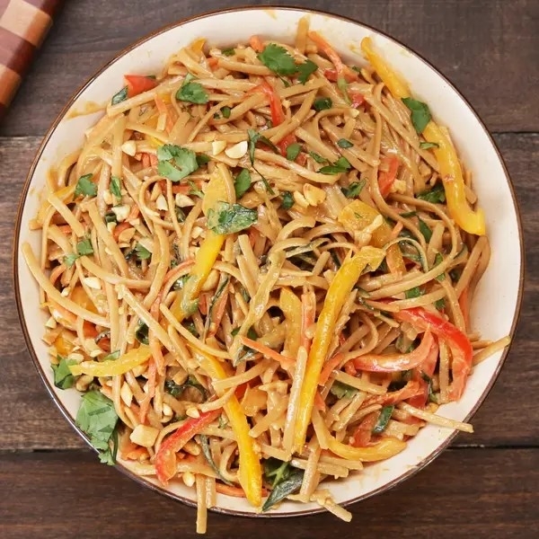 A bowl of vegetable pad Thai with mixed bell peppers and herbs