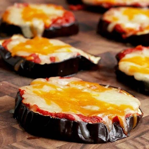Slices of eggplant topped with melted cheese and tomato sauce, resembling mini pizzas