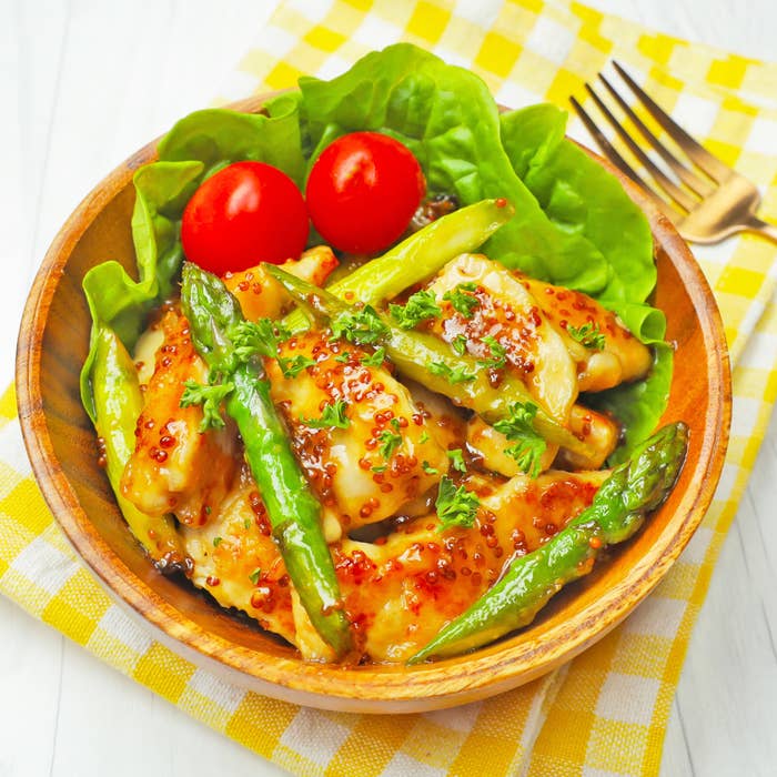 鶏肉とアスパラガスの料理が入った木のボウルがテーブルにあります。