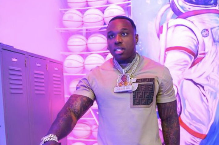 Rapper in locker room wearing chain necklaces and a printed jacket