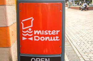 ミスタードーナツの看板、上部にキャップをかぶったドーナツのキャラクターが描かれている。