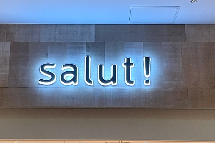 店内の壁に「salut!」のネオン看板が掲げられている。