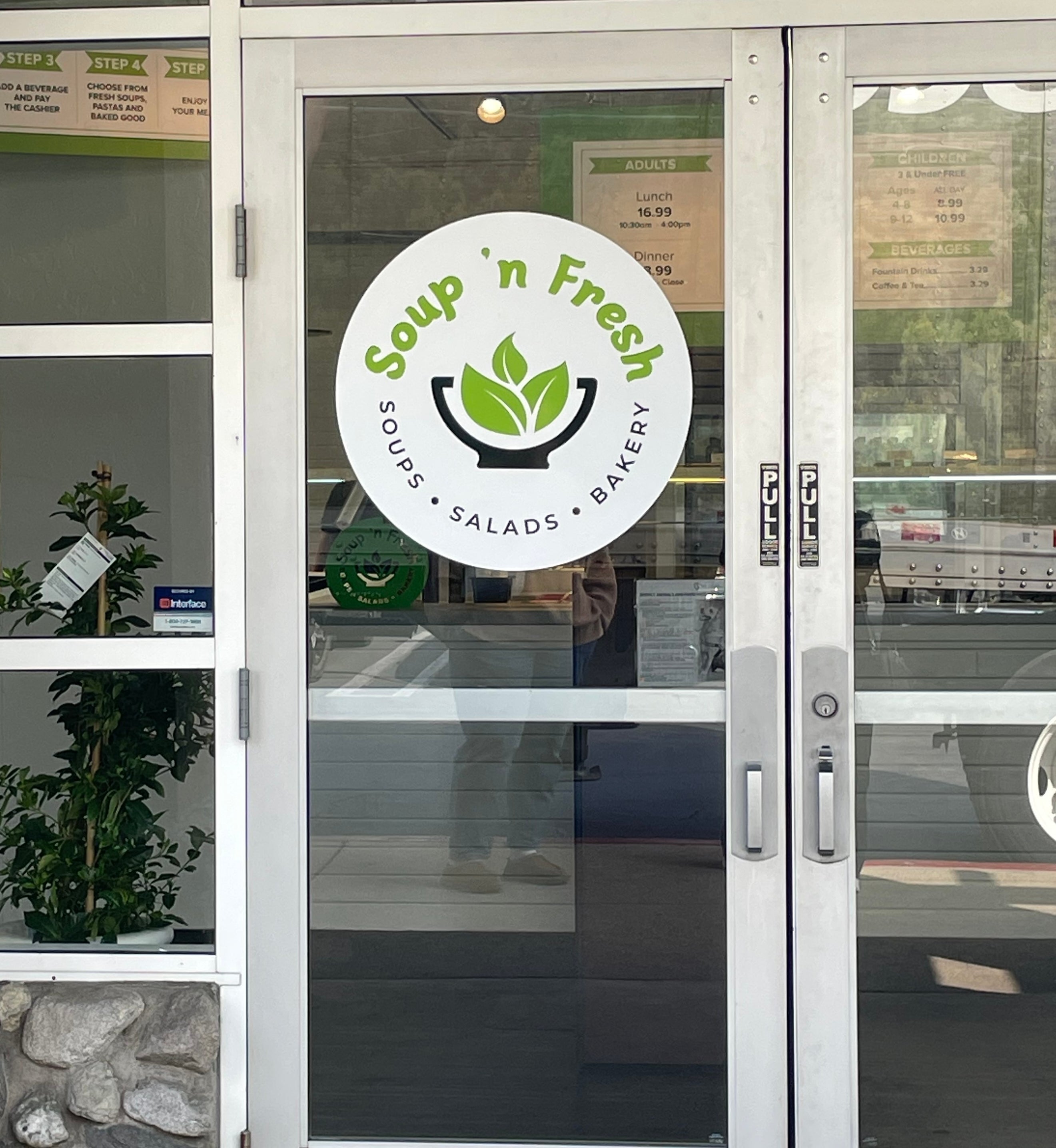 Glass door to a restaurant named &quot;Soup &#x27;n Fresh&quot;, indicating it serves soups, salads, and baked goods