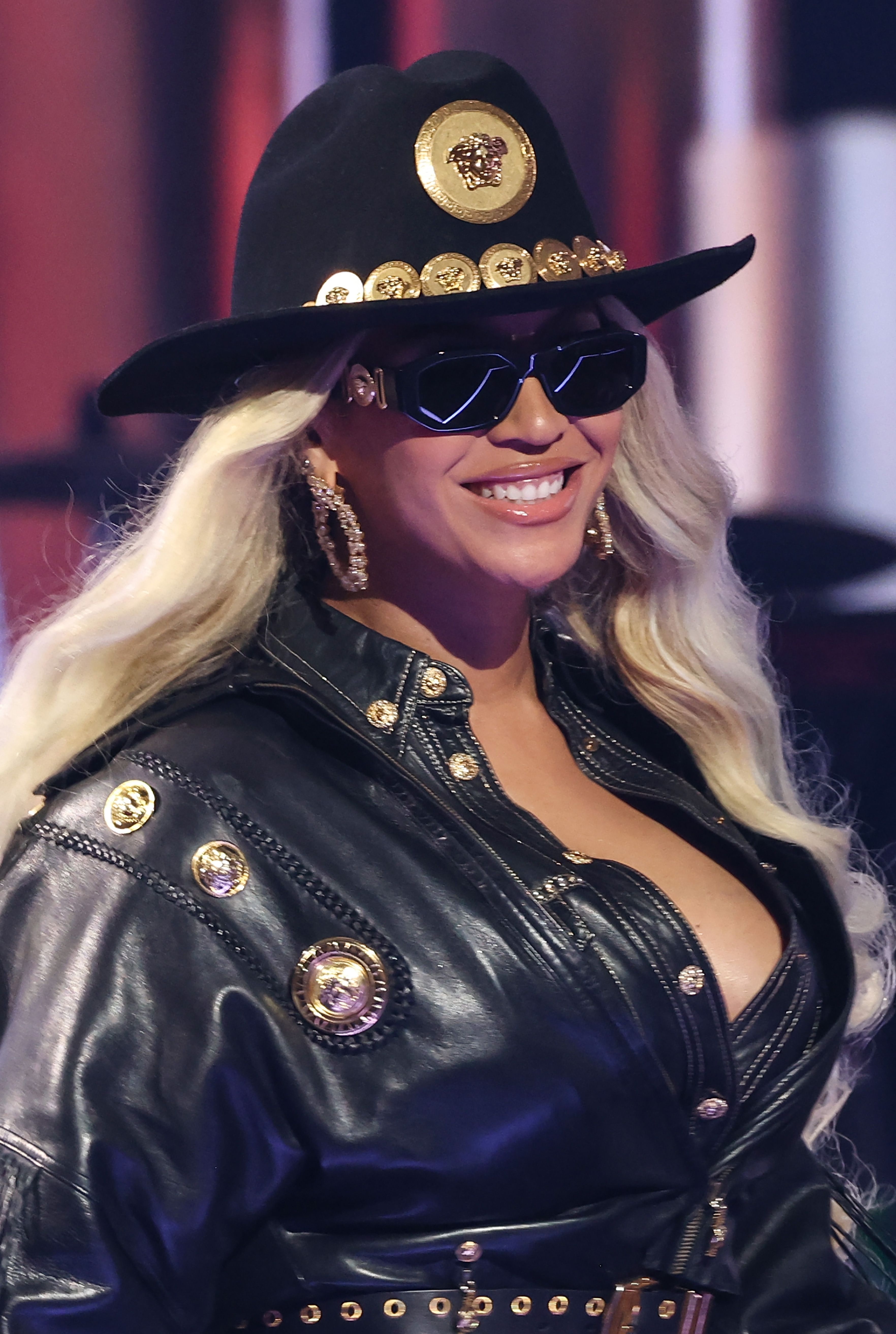 Closeup of Beyoncé in a leather cow-boy inspired outfit with a matching cowboy hat and sunglasses