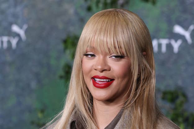 RIhanna smiling in front of a backdrop with logos