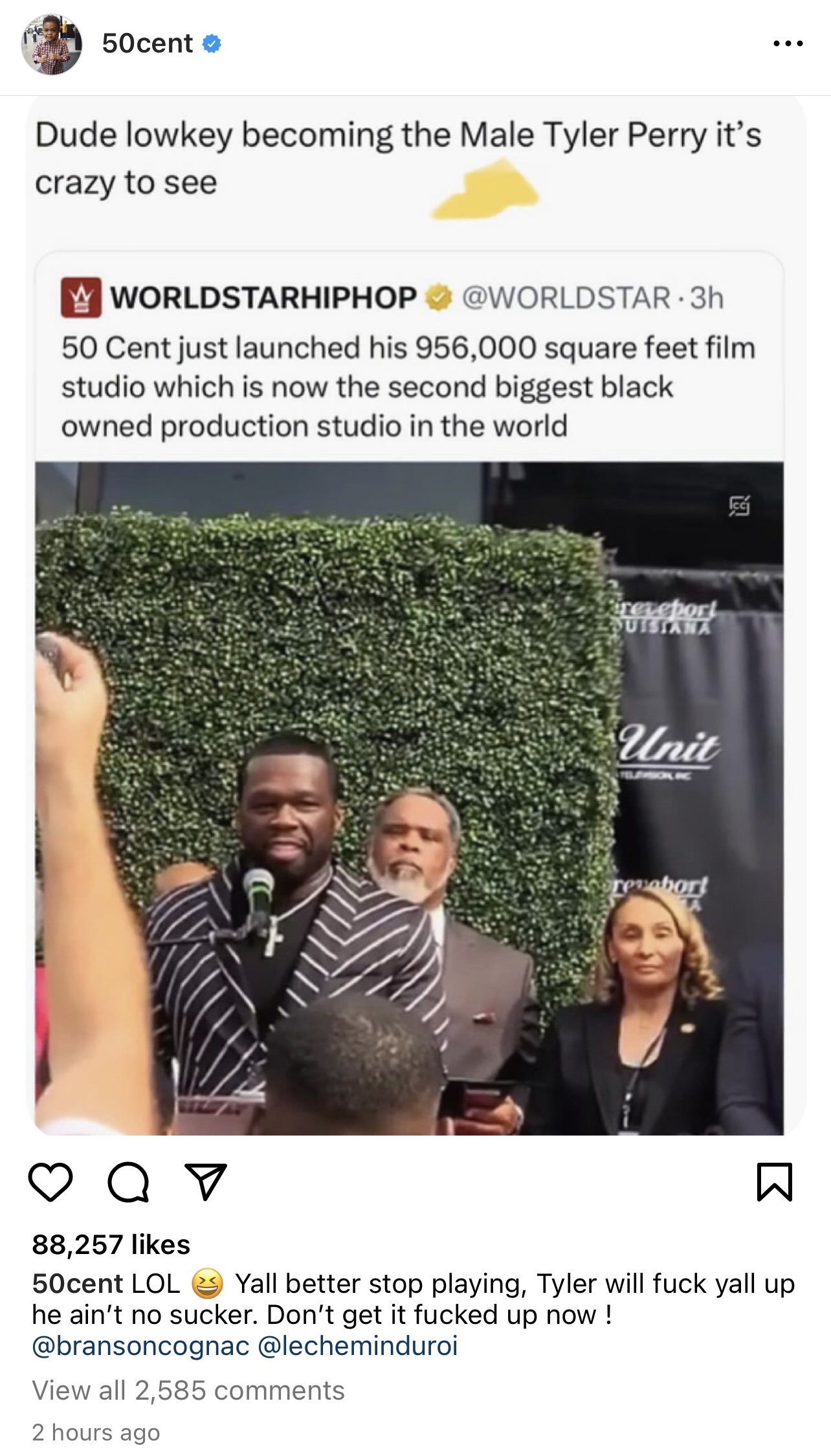 Curtis &quot;50 Cent&quot; Jackson raises his arm in excitement, behind him is Tyler Perry and other individuals at an event