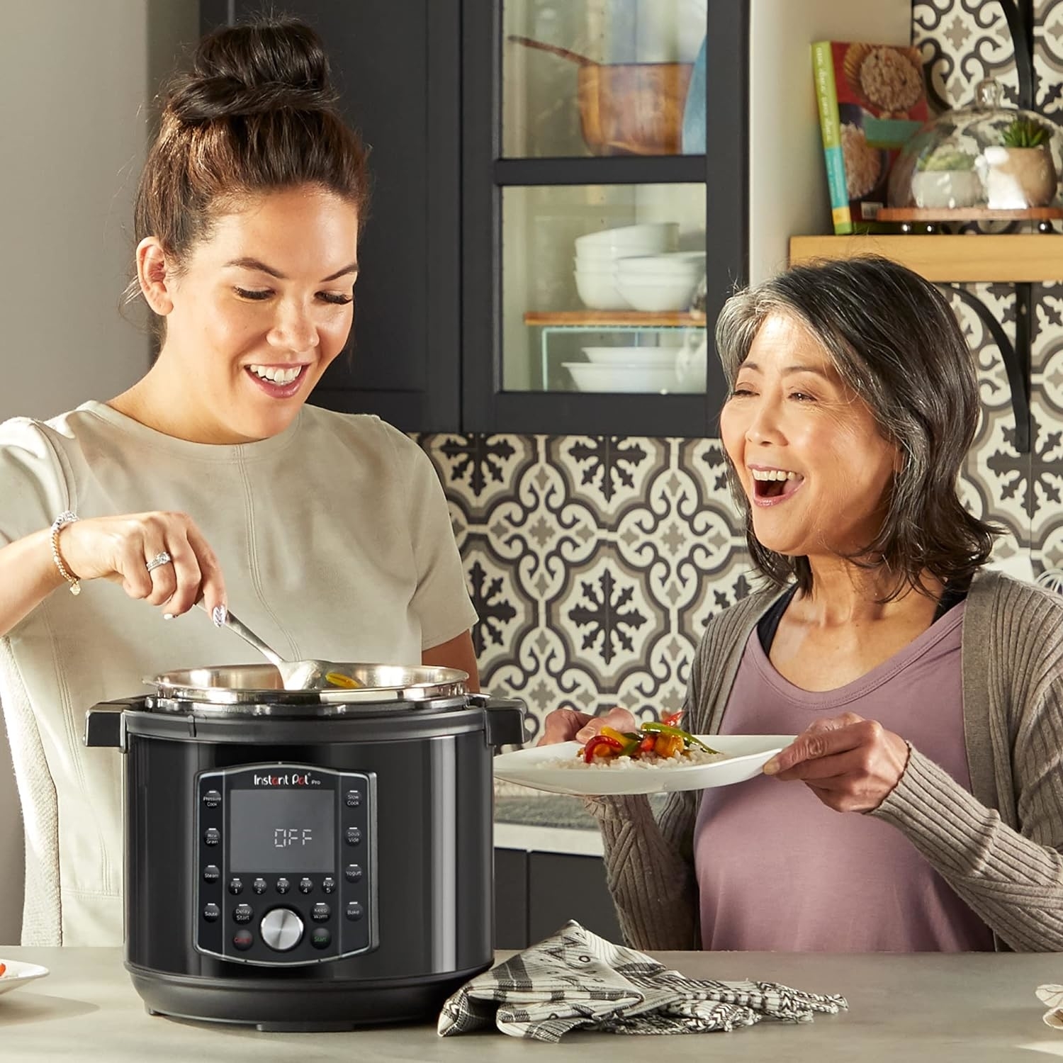 Two women cooking together with a modern electric pressure cooker in a home kitchen