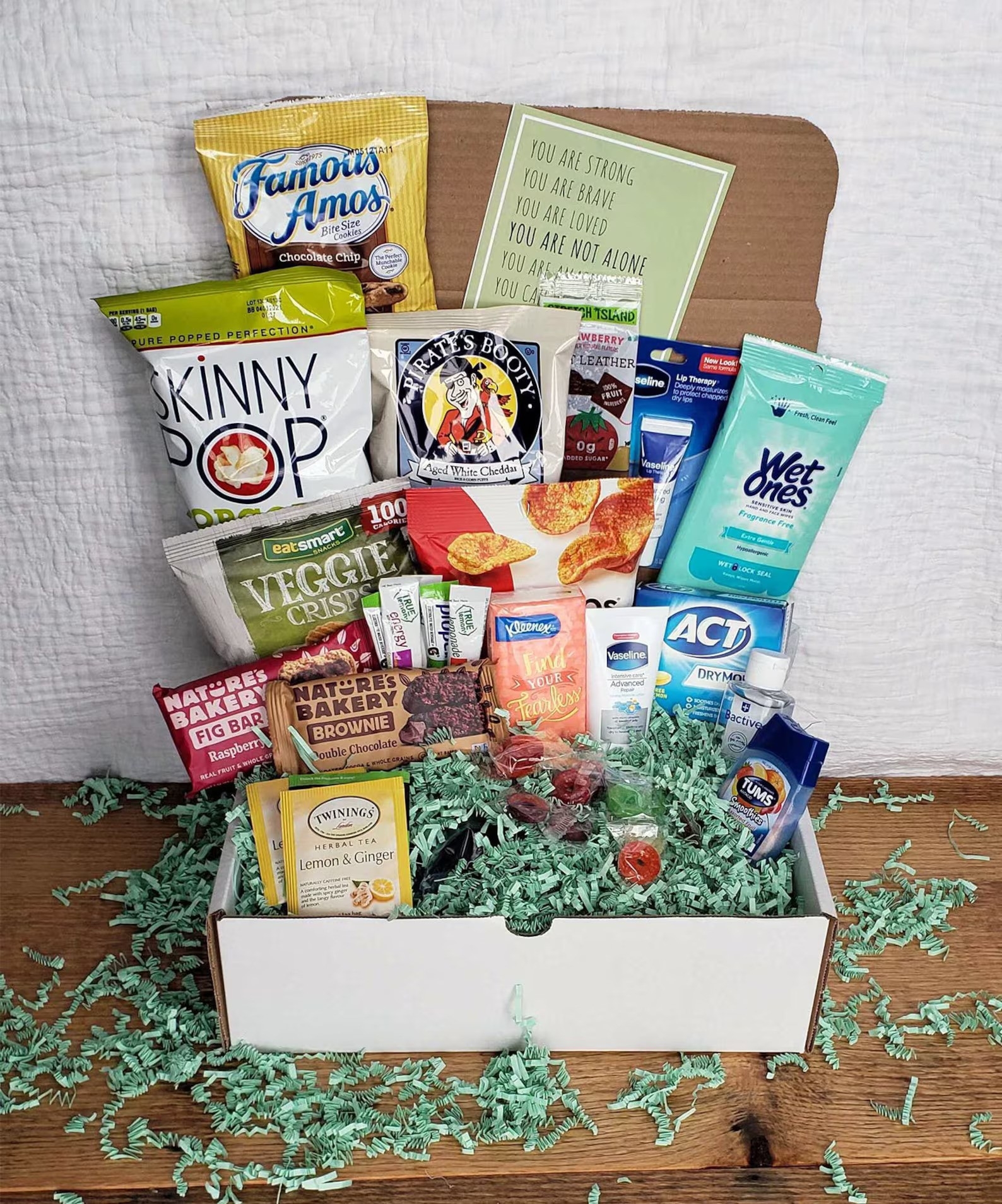 Assorted snack gift basket with inspirational message cards among various treats and self-care items