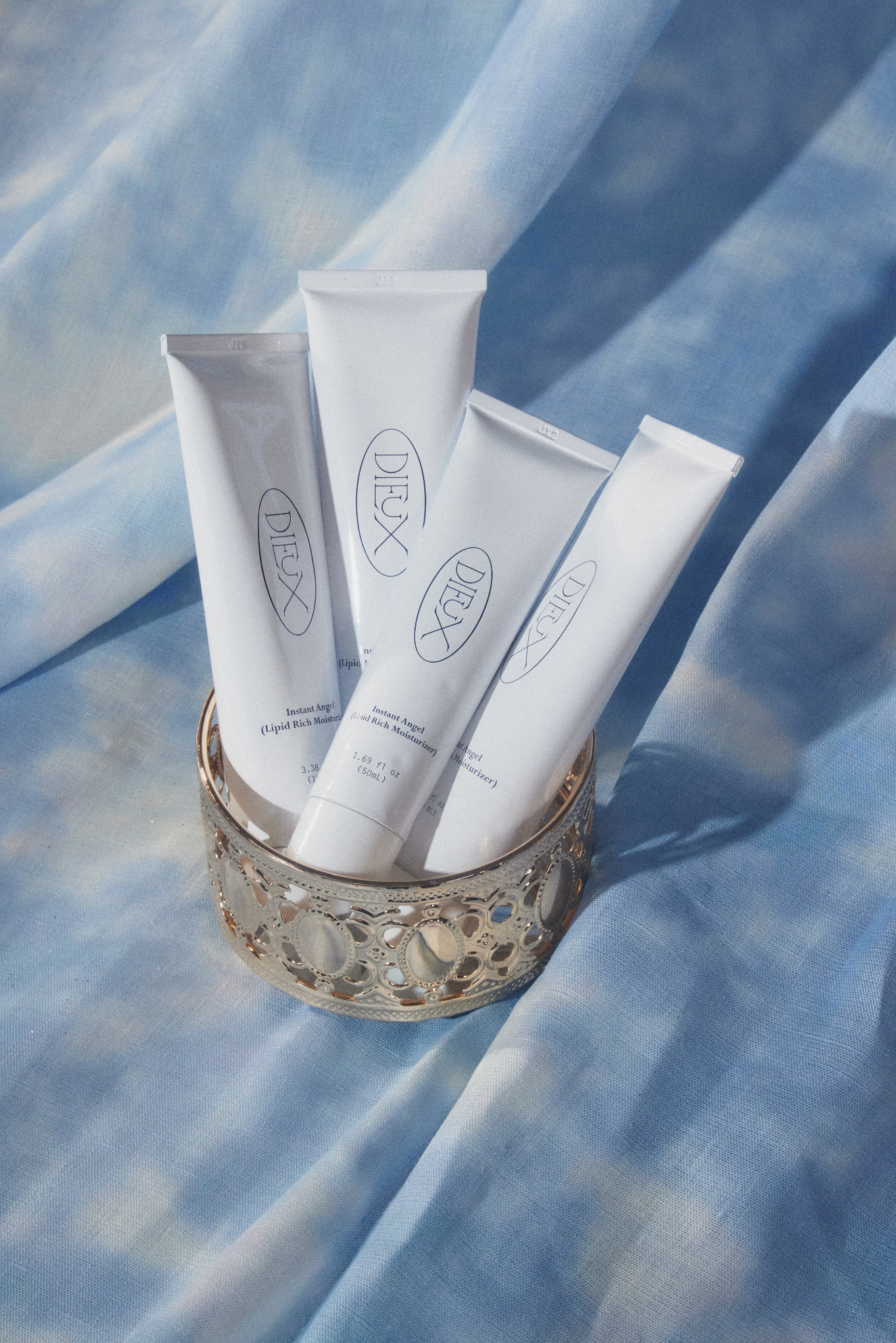Five skincare tubes in a decorative holder on a patterned fabric